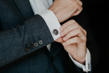 Close-up of a man in a tux fixing his cufflink.