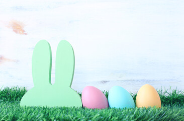 Cute bunny next to easter colorful eggs over pastel background