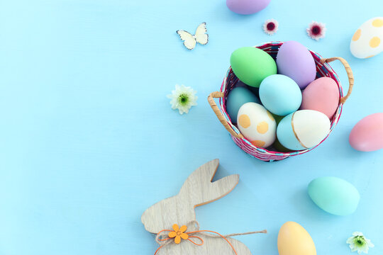Cute bunny next to easter colorful eggs over pastel background