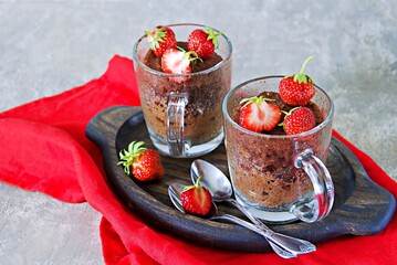Chocolate muffin in a glass mug, decorated with fresh strawberries and mint leaves.