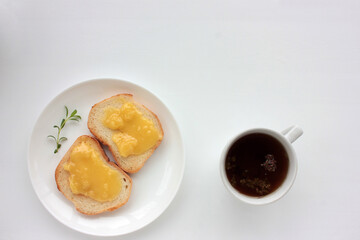 Cup of black herbal tea and toast bread with organic honey on plate on white table background....