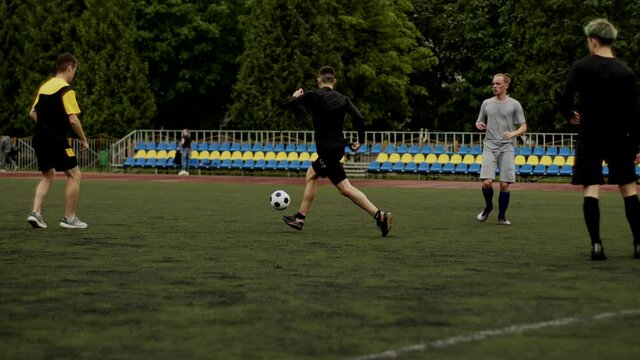 Friends play soccer and give a pass to each other. Football amateur game in a small stadium. Workout training. Team friendly match. Sport