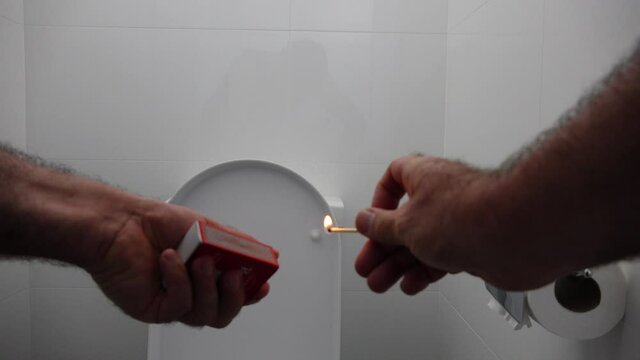 Person lighting match in restroom to get rid of bed odors.