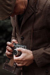 photographer with a retro camera in his hands. Dressed in retro style, jacket and cap - 417547114