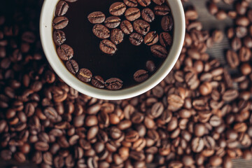 aromatic drink in a cup and coffee beans scattered on a wooden background