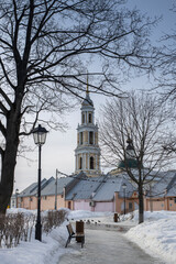 Fototapeta na wymiar Square in winter with a view of the bell tower. bench and lantern. tree in the park in the foreground.