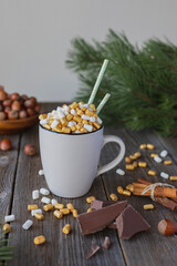 A mug of hot chocolate or cocoa, decorated with gold and white marshmallows, on a wooden table. Vertical orientation. Place for your text. Hot autumn and winter drink