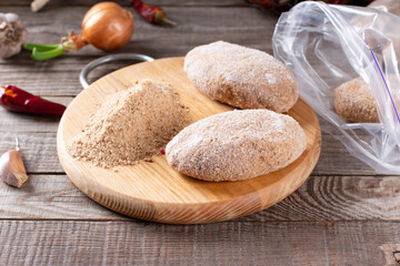 Frozen cutlets lie on a wooden board. Raw meat semi-finished products