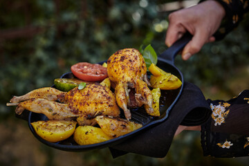 Faceless chef with yummy grilled quails and vegetables for garnish