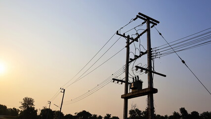 Silhouette of a transformer on a power pole. High voltage transmission lines and three-phase...
