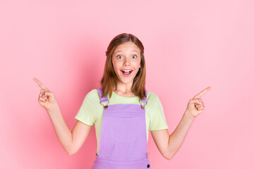 Photo portrait of small girl amazed pointing fingers up copyspaces isolated on pastel pink color background