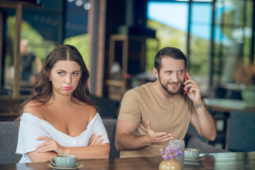 Offended woman and inattentive man talking on smartphone