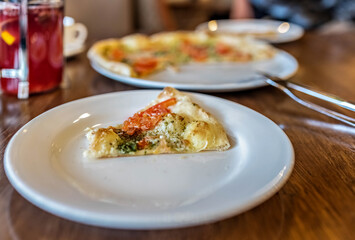 A slice of vegetarian pizza on a white plate. Served table in an Italian restaurant