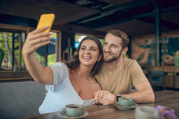 Smiling woman and man taking selfie on smartphone