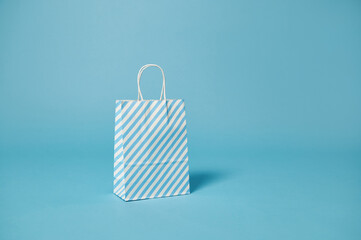 A paper bag with white-blue stripes on a blue background with copy space for promotion. Advertising