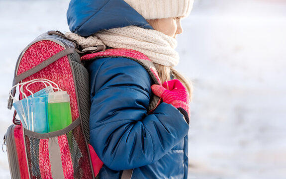 Pink backpack with hand sanitizer (hand rub) and medical face shield. The briefcase is not on the child's back. Back to school. Prevention of viruses and diseases in children.