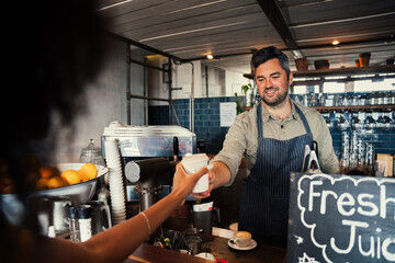 handsome male barrister serving woman freshly made hot coffee in funky cafe 