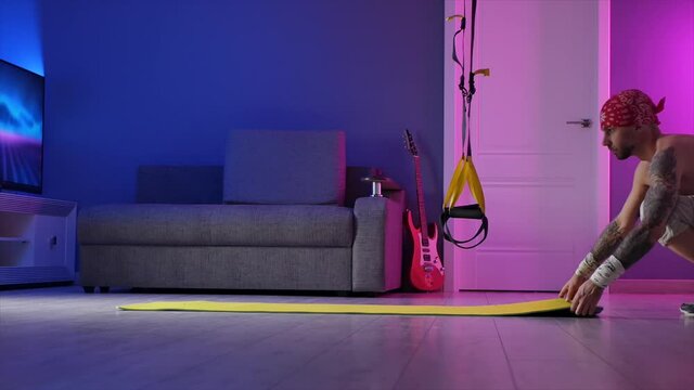 a guy with a sporty physique trains sports at home on hinges neon light in the room