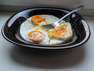 photo of fried eggs in a black plate on a white background.  food photo