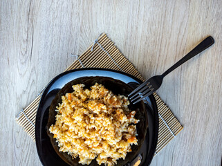 photo of pilaf in a black plate on a white background. rice dish. photo of food.  View from above. 