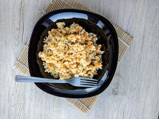 photo of pilaf in a black plate on a white background. rice dish. photo of food.  View from above. 
