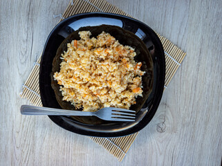 photo of pilaf in a black plate on a white background. rice dish. photo of food.  View from above. 