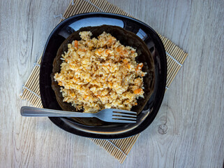 photo of pilaf in a black plate on a white background. rice dish. photo of food.  View from above. 