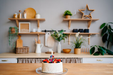 cake with candle number two and fruit on table on Scandinavian-style kitchen 