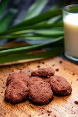 Delicious homemade chocolate cookies on a wooden plate with milk as a background