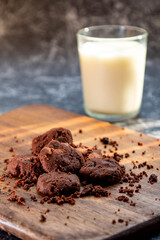 Delicious homemade chocolate cookies on a wooden plate with milk as a background
