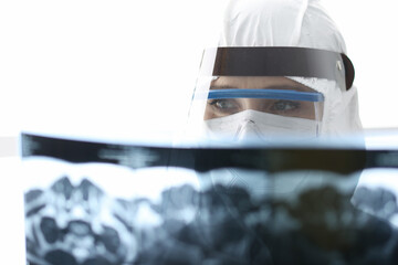 Doctor in protective antiplague suit looking at xray. Diagnostics of covid pneumonia concept