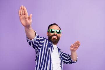Naklejka premium Photo of positive mature man in sunglass hold hands dance isolated over purple color background