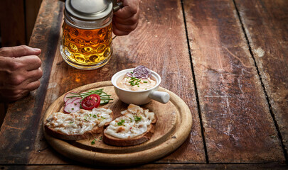 Faceless person with mug of beer and appetizing appetizer