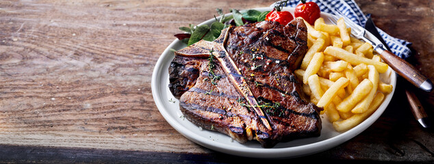 Tasty porterhouse steak with French fries on plate