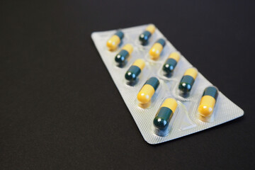 plate with yellow and green capsules on black background side view