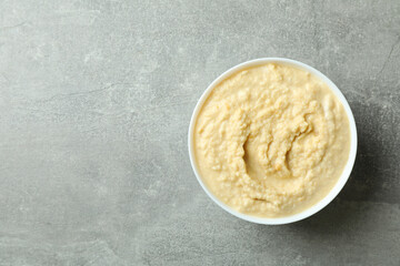 Bowl of fresh hummus on gray background