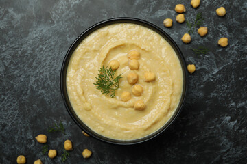 Bowl of fresh hummus on black smokey background