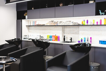 Beauty salon barbershop interior. Large comfortable black leather armchairs in a modern, cozy and bright room.