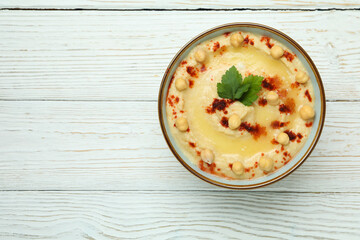 Bowl of hummus on white wooden background