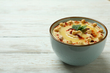 Bowl of hummus on white wooden background