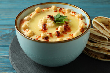 Tray with bowl of hummus and pita on wooden background