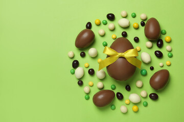 Easter chocolate eggs and candies on green background