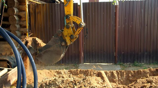 Excavator digs out old root making trench near fence