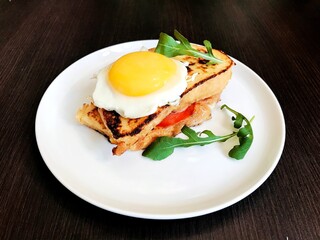 toast with cheese and meat on top of scrambled eggs with herbs.