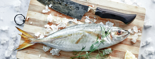 Uncooked horse mackerel on cutting board with knife
