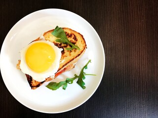 toast with cheese and meat on top of scrambled eggs with herbs