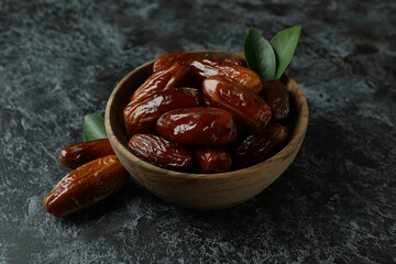 Wooden bowl of dates on black smokey background