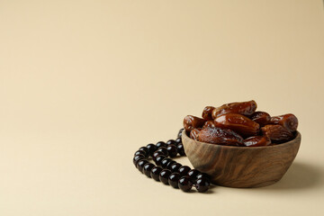 Rosary and bowl with dates on beige background