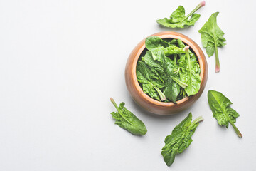 Fresh spring spinach leaves in a wooden bowl on a white background. Fresh vitamin rich greens. Copy space for graphic design
