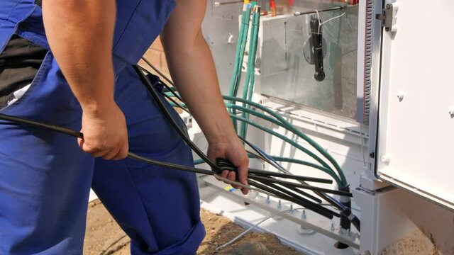 Worker puts insulation on wires in switchbox case in street